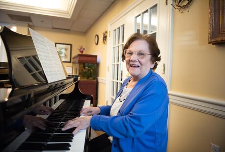 A resident playing the piano at Legacy at Clover Blossom senior living community in Rochester.