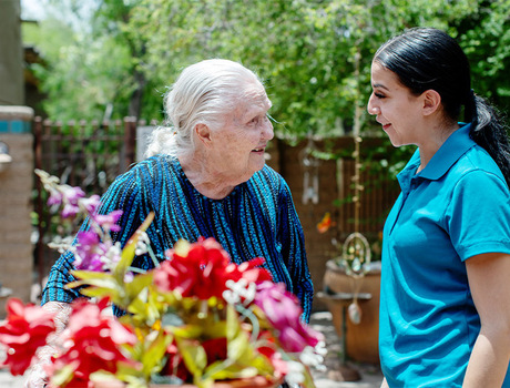 A person with a caregiver out in the courtyard garden.