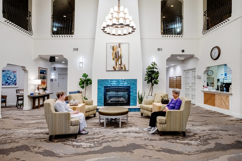 A lobby with people sitting in chairs.