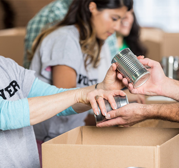 People volunteering taking in canned food.