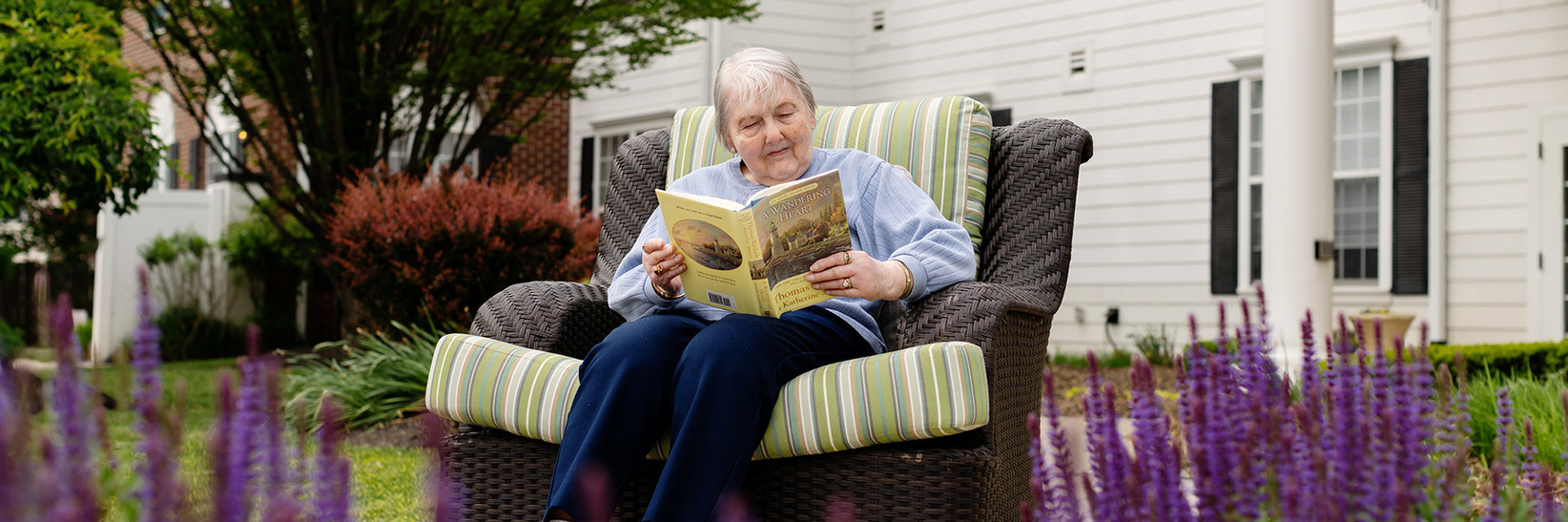 A person reading a book out in the garden at Blue Bell Place senior living community.