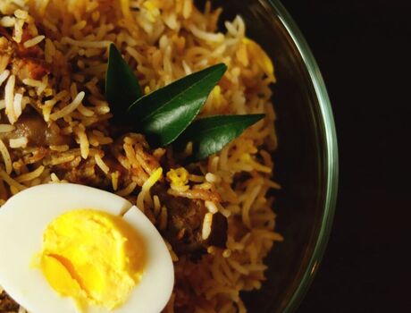 A bowl of chicken biryani with a boiled egg on top.