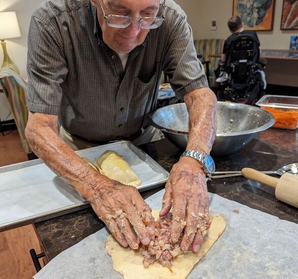 Tony, a resident, placing a filling in rolled out dough.