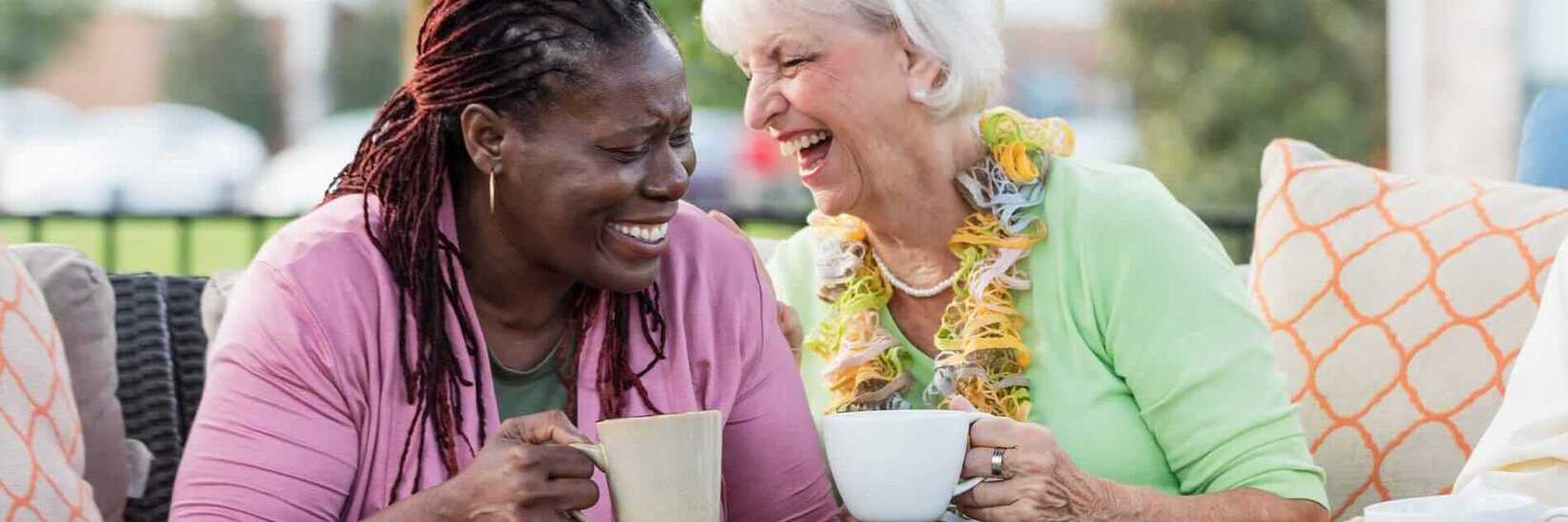 Two residents laugh with coffee.