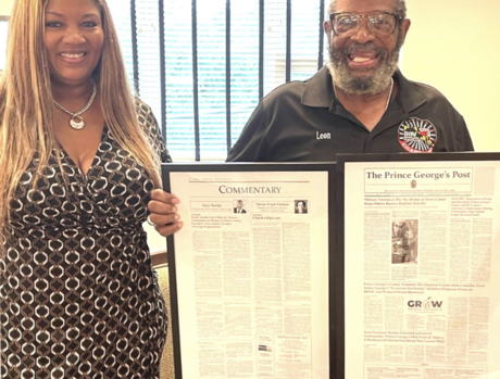 Veteran and Associate holding framed newspaper article.