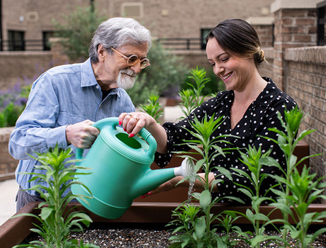 A person helping a resident water plants.