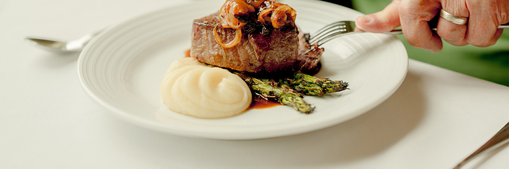 A person cutting into a steak. A person cutting into a steak.