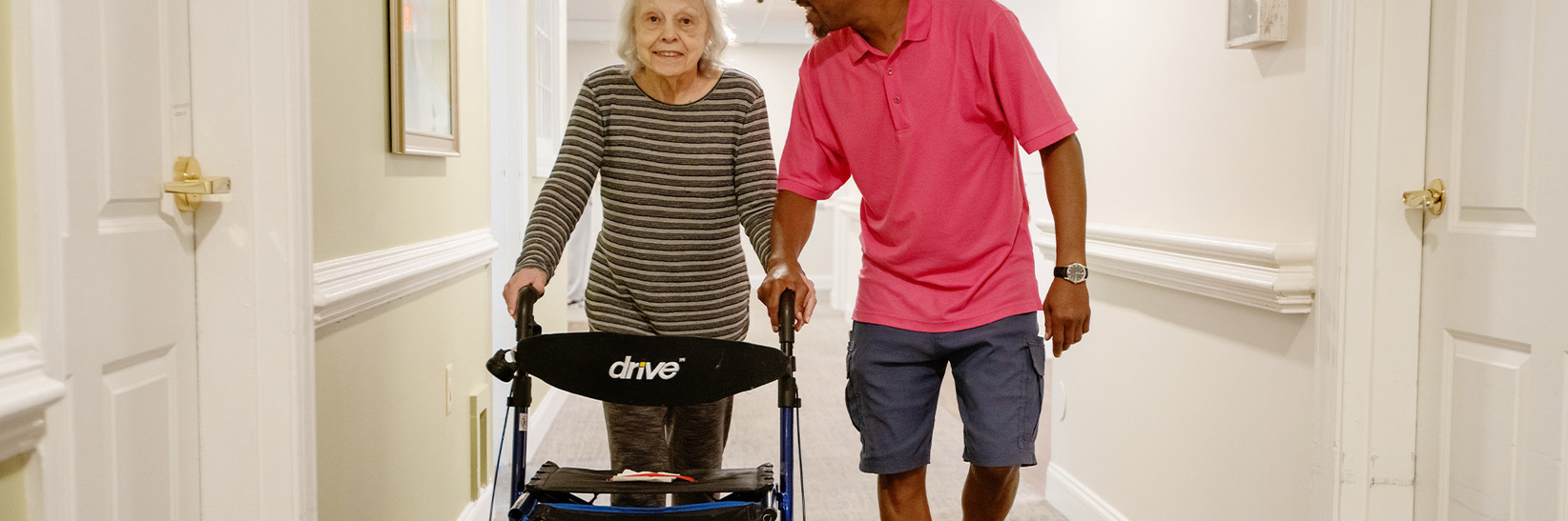 A person helping a resident walk.