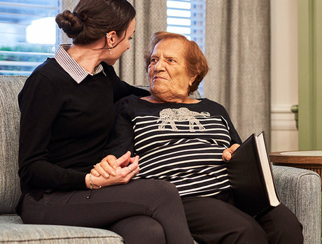 A person sitting with a resident on the couch.