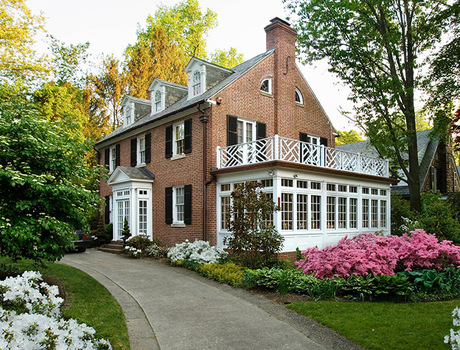 An old colonial style brick house surrounded by a garden.