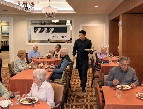 The Mark restaurant with members eating a meal and a server holding a tray.