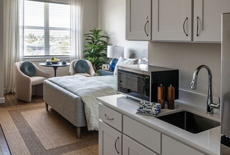 Studio apartment with a window, bed, and kitchenette.
