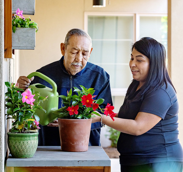 A caregiver helping a resident water plants.