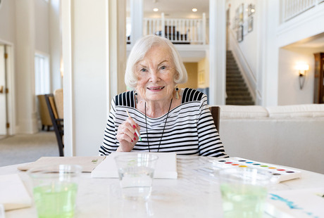 A resident is sitting at a table painting.