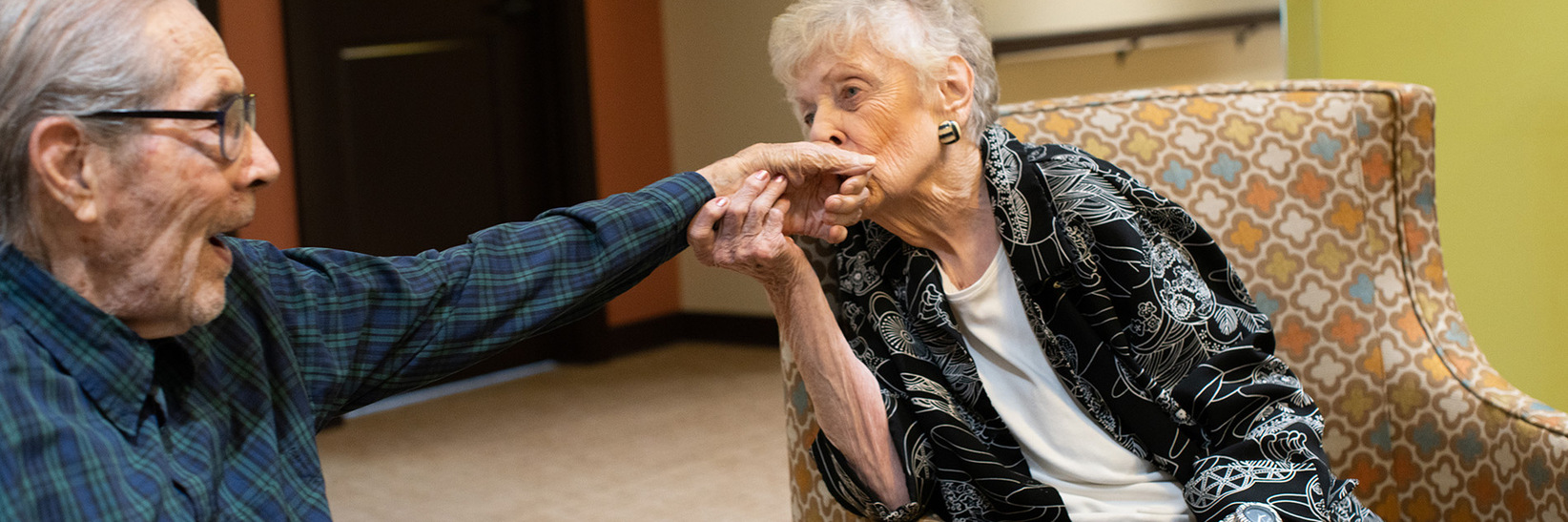 A resident is kissing another residents hand. A resident is kissing another residents hand.