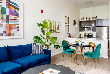 A fully furnished living room looking into the dining kitchen area.