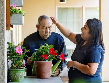 A naya caregiver helping a resident water plants.