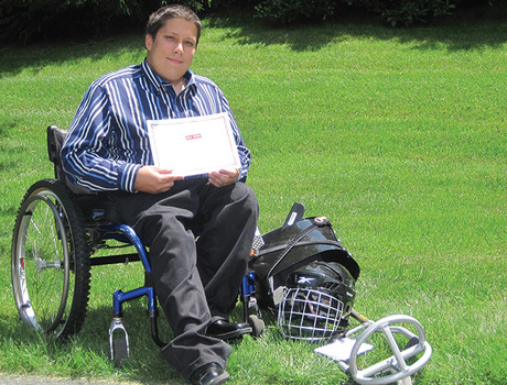A teen sitting in a wheel chair with their sled hockey equipment.