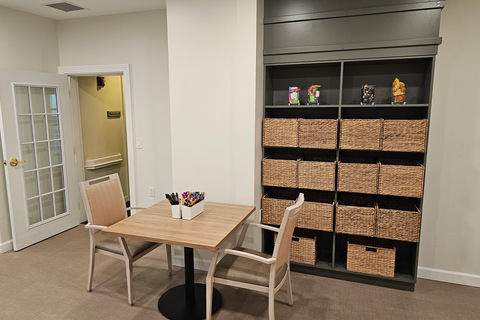A table and chairs with baskets on the shelf.