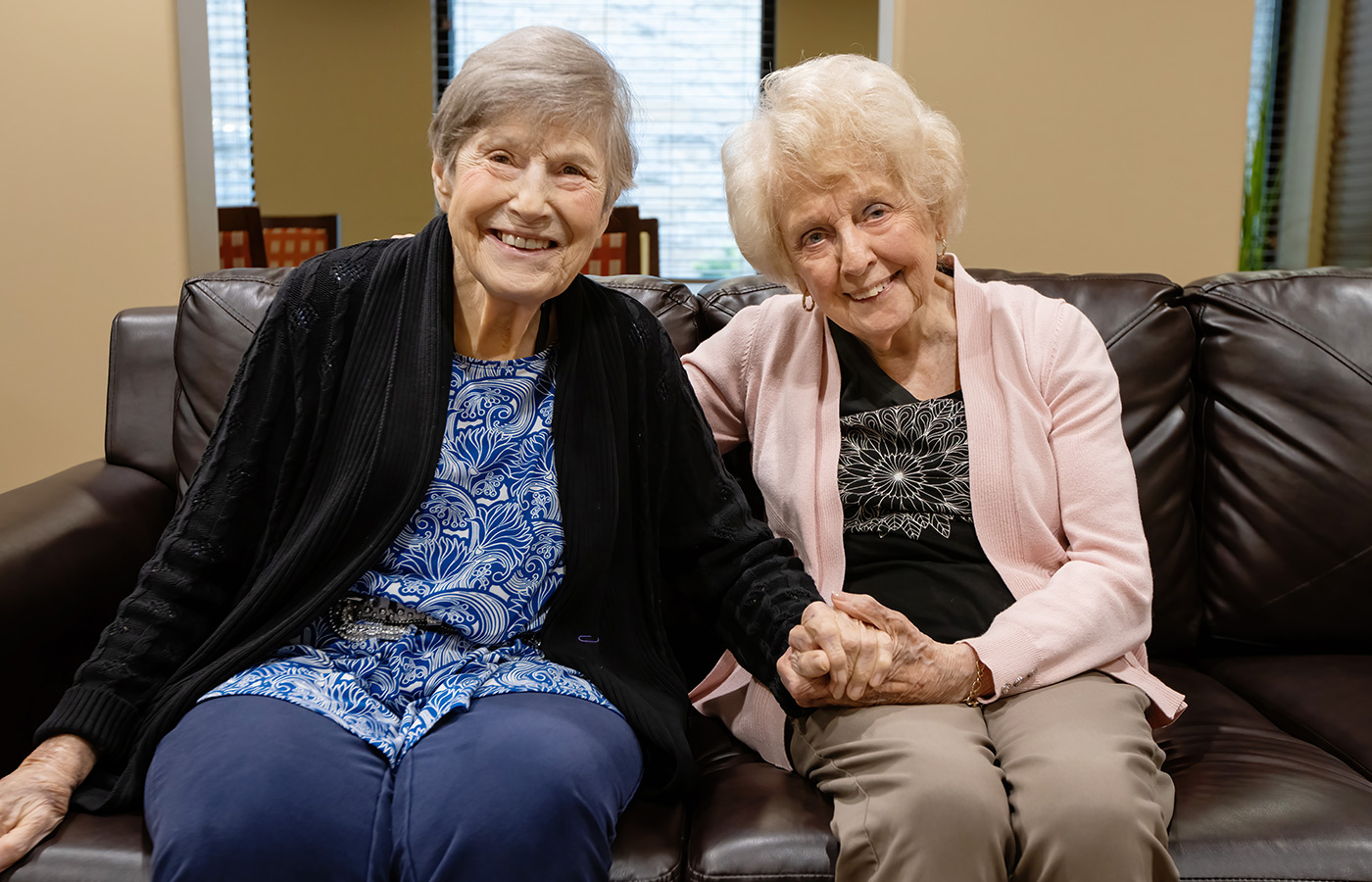 Two residents on the couch holding hands.