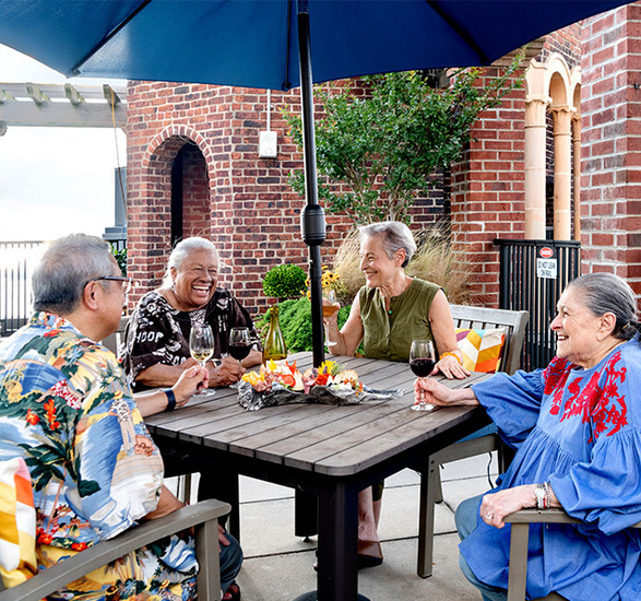 A group of residents are enjoying snacks and beverages on a patio.