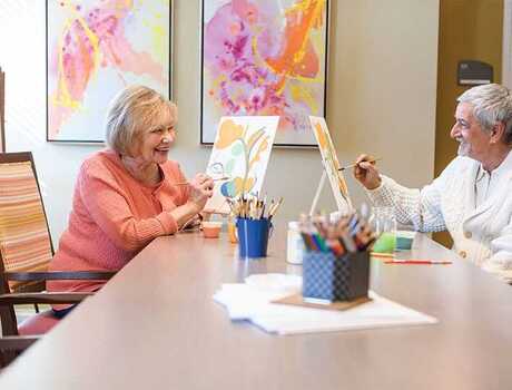 Residents enjoying an art class with canvases and paint brushes.