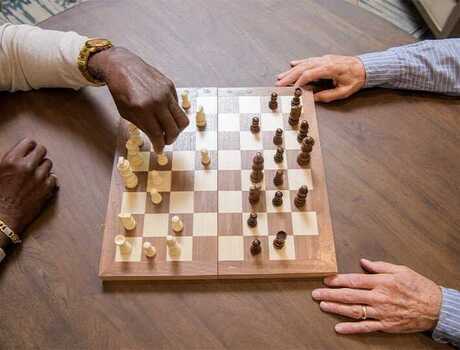 A pair of hands are visible on either side of a wooden chess board