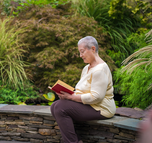 A resident is reading by a koi pond.