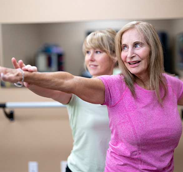 A person helping another stretch.