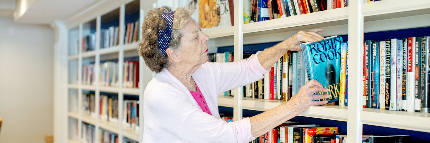 A person pulling a book from the shelf. A person pulling a book from the shelf.