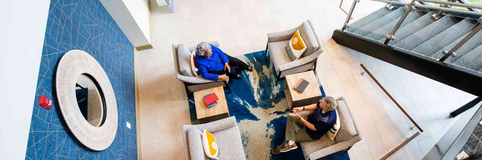 Two residents talking in the lobby while sitting on chairs.