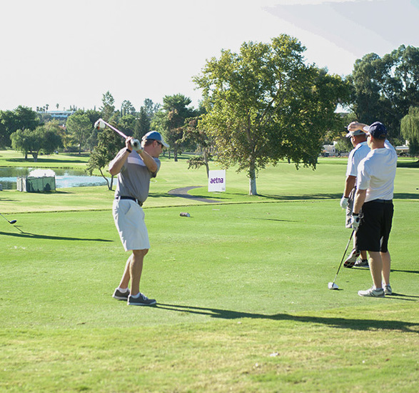 People swinging clubs on a golf course.