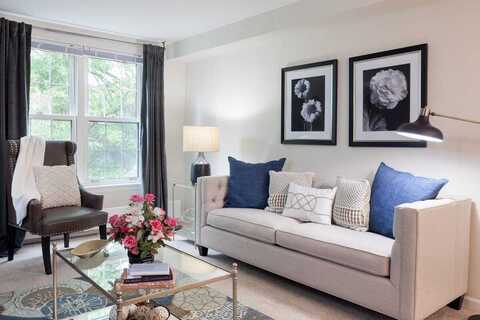 Furnished living room space with sofa, large window, coffee table, and arm chair.