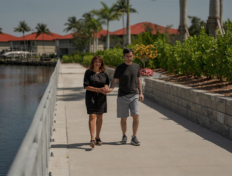 Two people walking by the water.