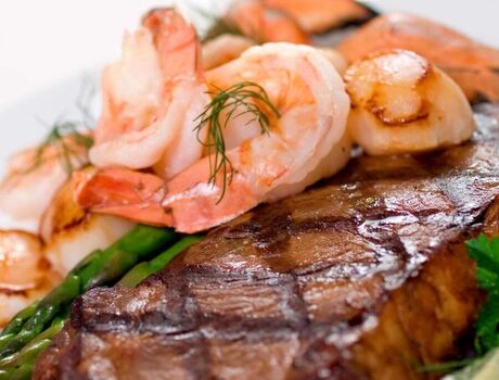Steak topped with shrimp and a side of asparagus.