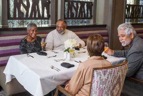 A group of residents seated in a booth in one of the on-site dining establishments at The Preston at the Park Cities