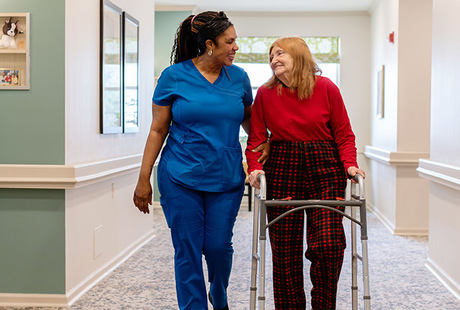 A caregiver helping a resident in the hall. at Blue Bell Place Senior Living Community
