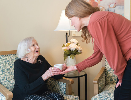 A person handing coffee to a resident.