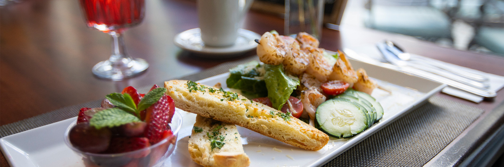 a close up of a plate of food consisting of strawberries, bread and a small salad with shrimp a close up of a plate of food consisting of strawberries, bread and a small salad with shrimp