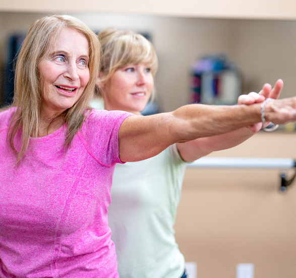 Caregiver helps stretch a resident's arm.