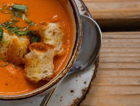 A bowl of tomato basil soup topped with croutons.