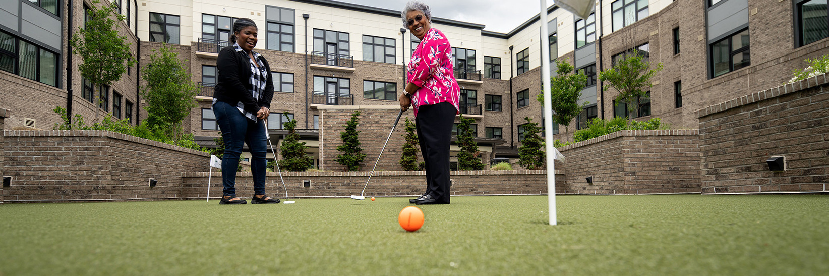 A resident and their adult child playing golf. A resident and their adult child playing golf.