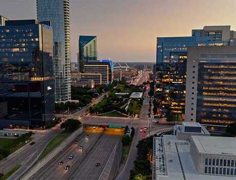 Aerial shot of Dallas on a summer evening, looking along the Woodall Rodgers Freeway (Spur 366) where it passes beneath Klyde Warren Park.