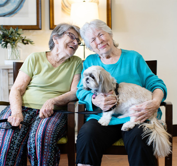 Two people sitting with a dog.