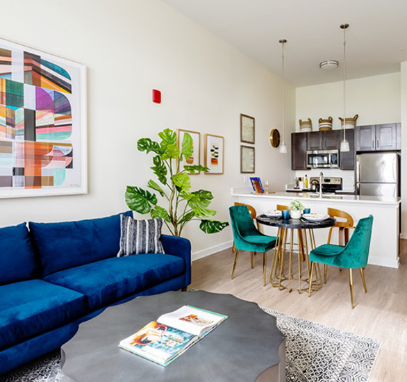 A fully furnished living room looking into the kitchen.