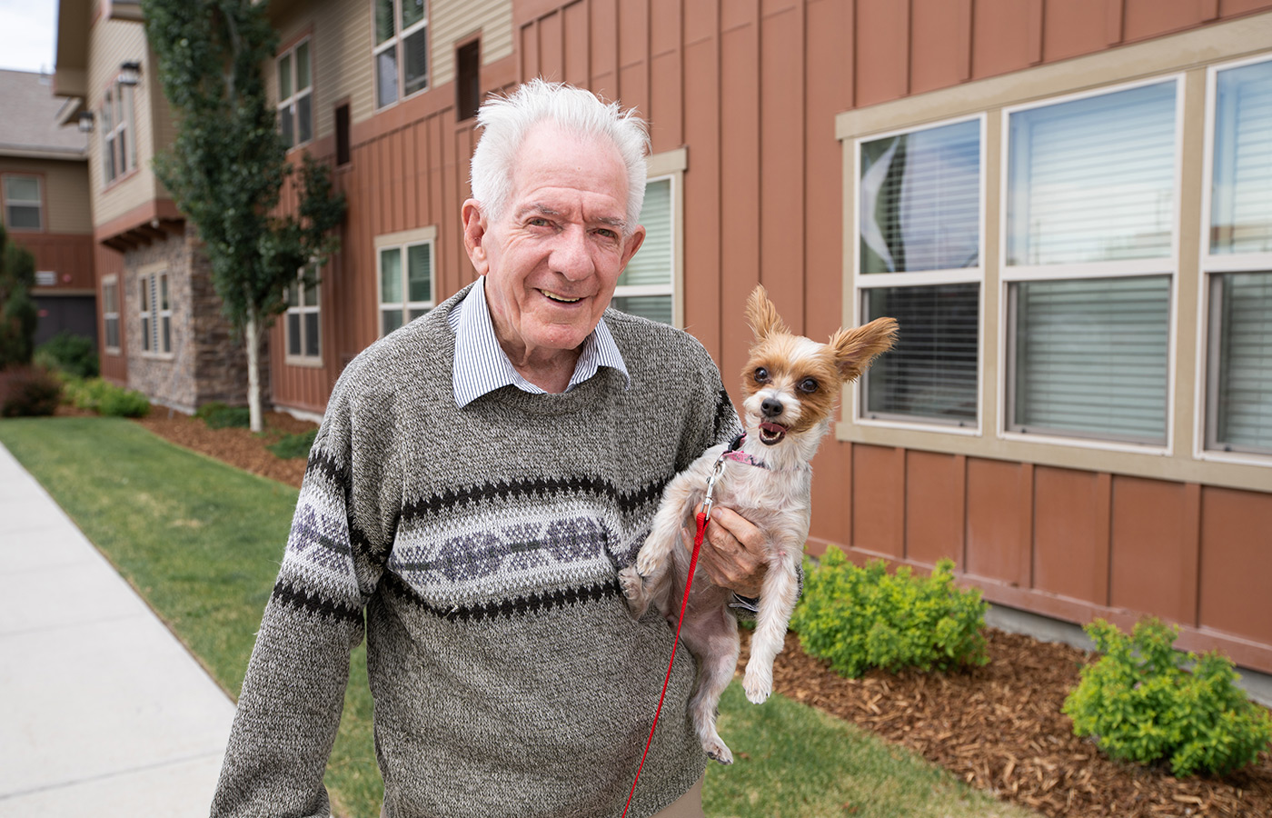 an elderly man outside holding a small dog