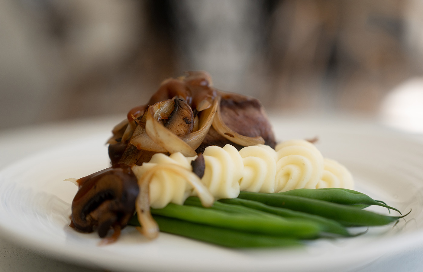 A plate with steak and green beans.