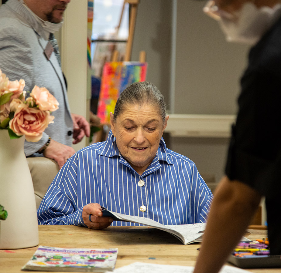 Elderly woman reading a book at a table A resident is reading a book at a table.