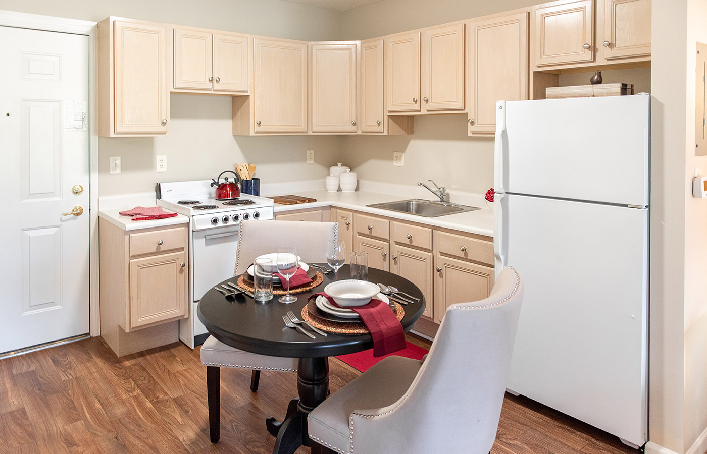 Furnished kitchen with table, cabinets, and refrigerator.