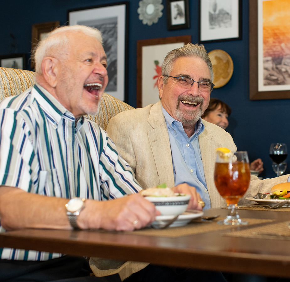 Two residents laughing while eating dinner.
